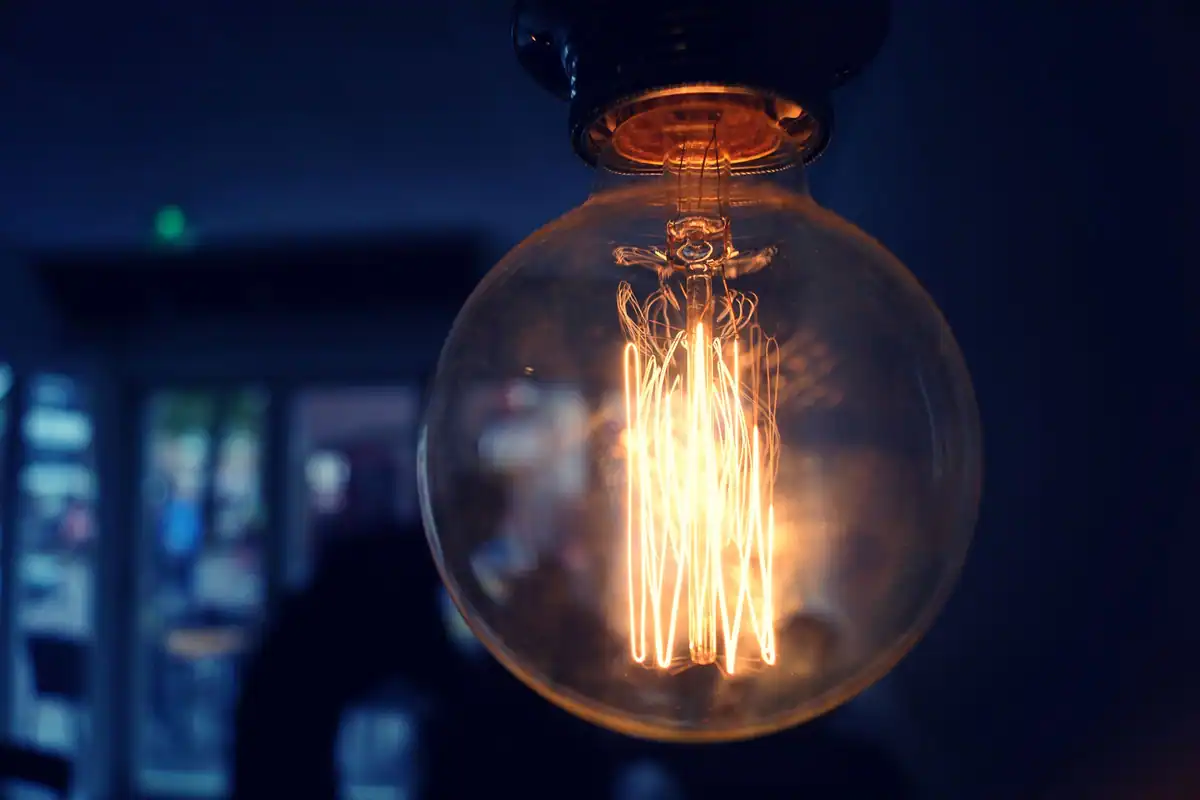 Bec cu filament de tip Edison care strălucește într-o încăpere întunecată