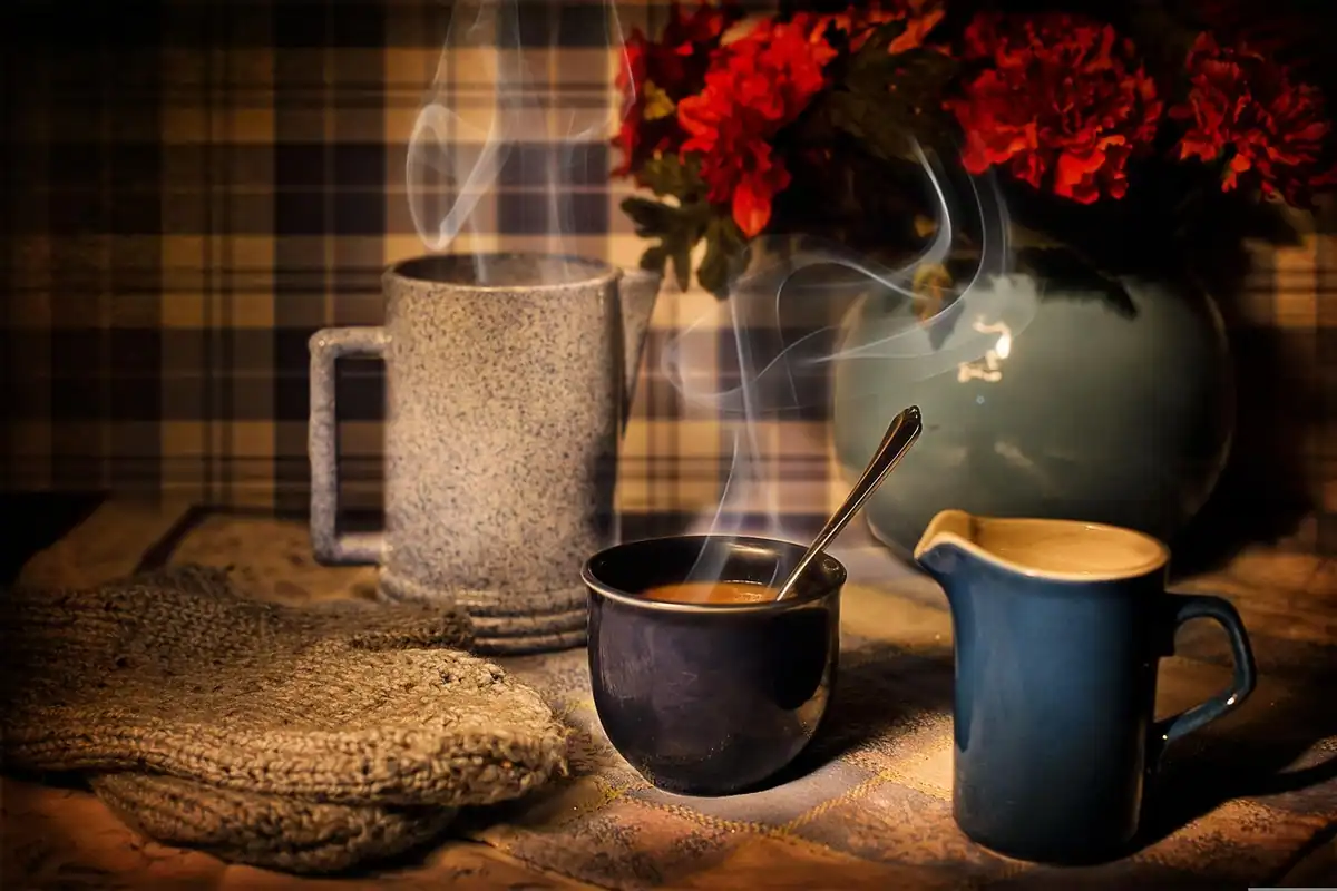 Cană caldă de cafea, lângă decorațiuni de iarnă, într-o atmosferă călduroasă