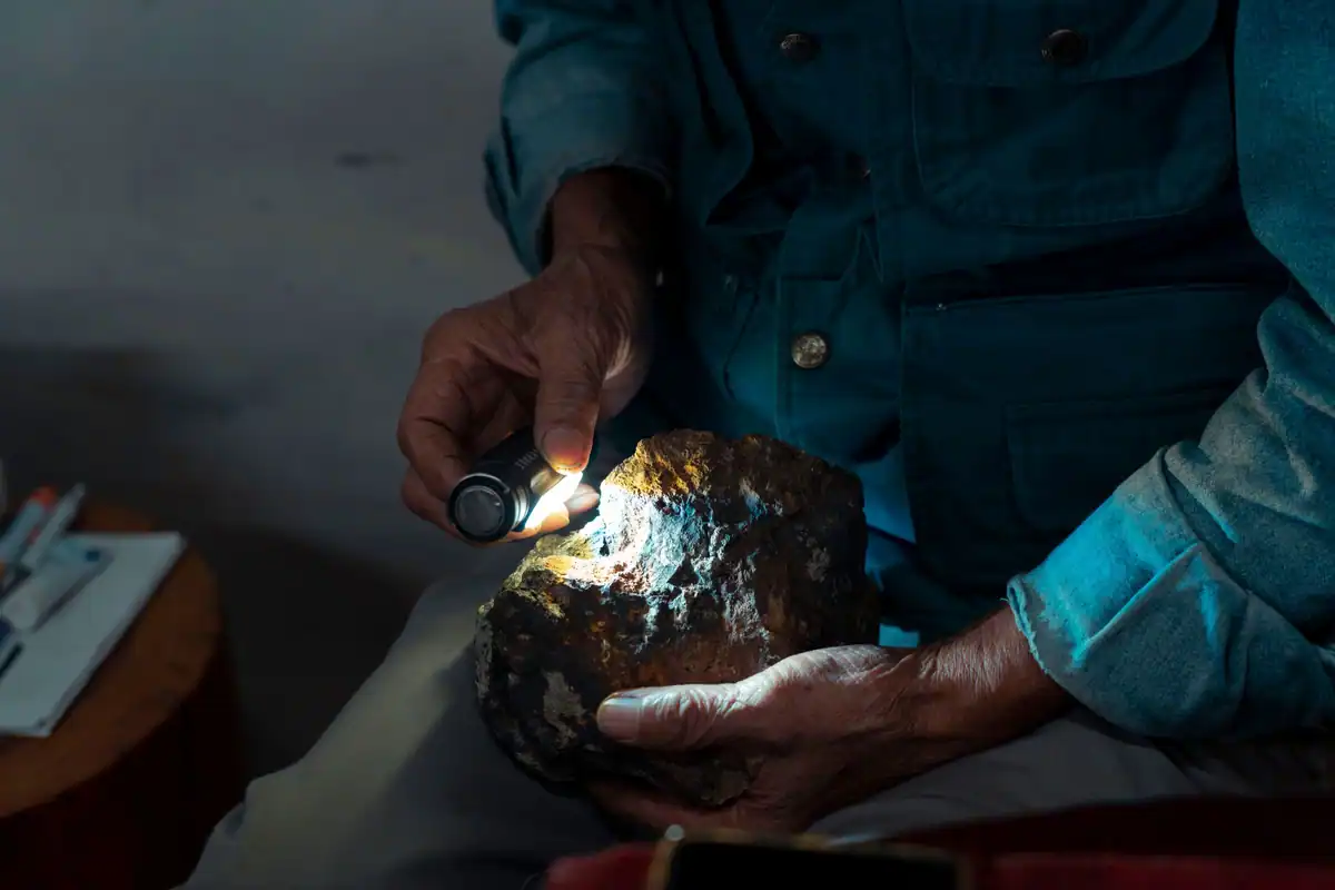 Mâini care examinează o rocă la lumina unei lanterne