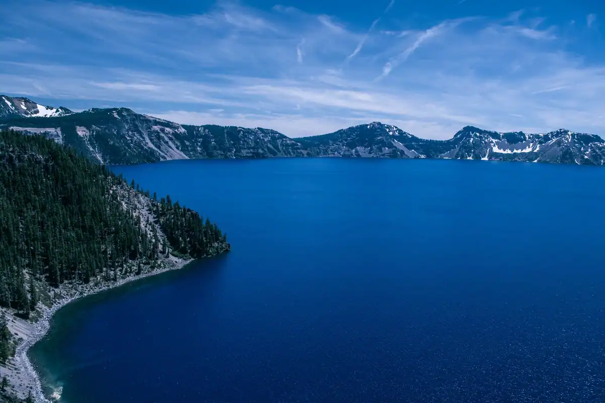 Lac format în craterul unui vulcan stins, înconjurat de păduri